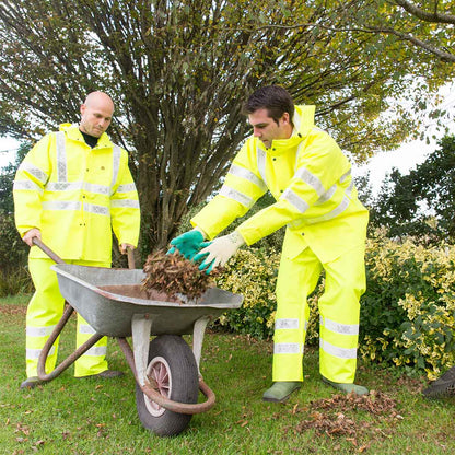 Two people in Guy Cotten yellow Isoflash and Poulflash high-visibility yellow rain gear working with a wheelbarrow outdoors.